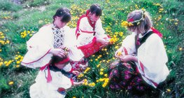 Dziewczęta plotą wianki z mleczy